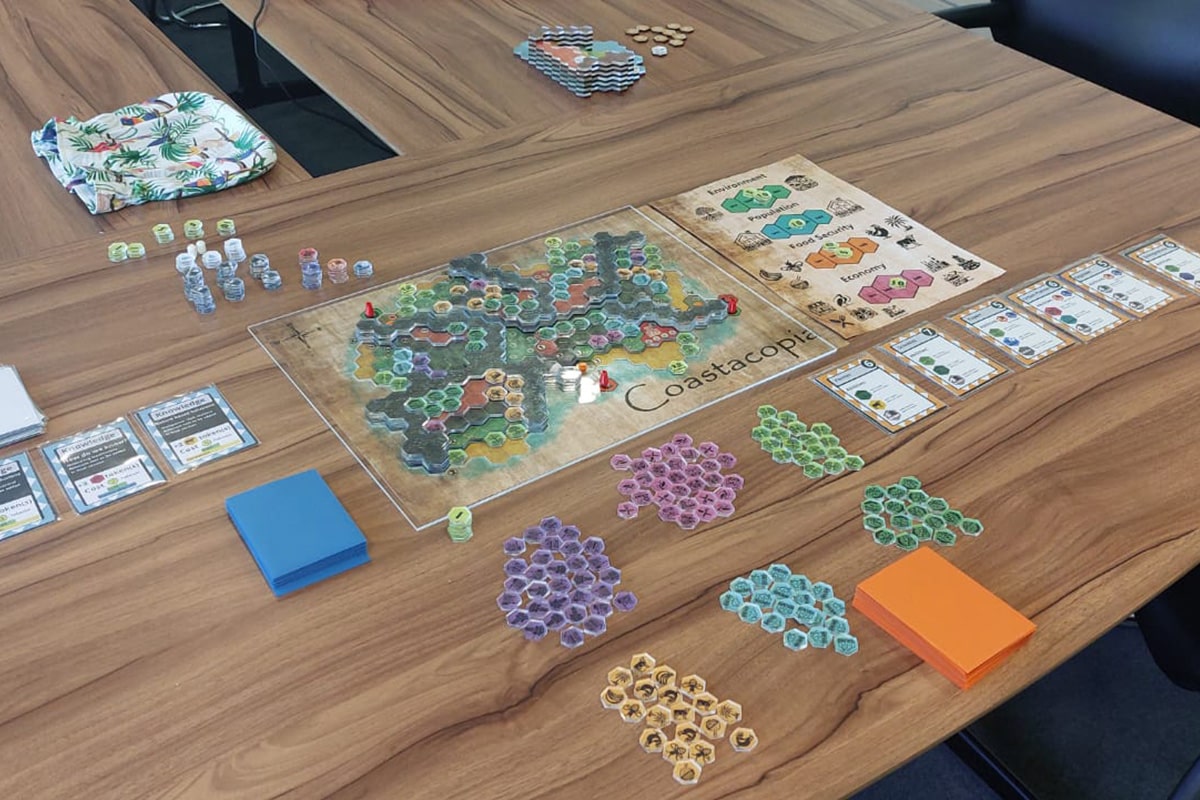 A board game laid out on a table with board, cards and playing pieces