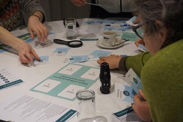 A group of three people seated round a table playing a game with cards